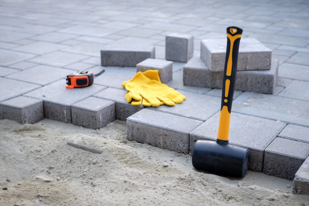 The master in yellow gloves lays paving stones