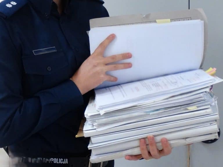 policjant trzyma akta sprawy