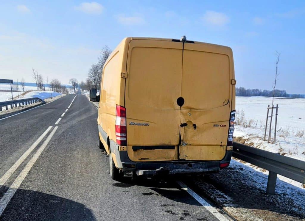 Ż&oacute;łty samoch&oacute;d dostawczy z uszkodzeniami na drodze wojew&oacute;dzkiej, zimowa sceneria, brak innych pojazd&oacute;w na drodze.