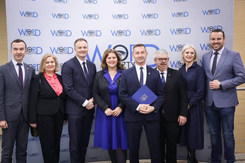 Grupa ludzi na tle logo WORD Włocławek, podczas oficjalnej uroczystości związanej z zakupem nowoczesnego rezonansu.