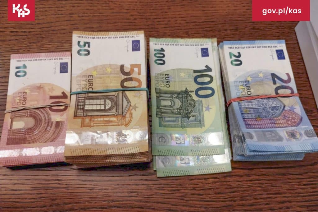 Na zdjęciu ułożone banknoty euro w r&oacute;żnych nominałach na drewnianym stole.