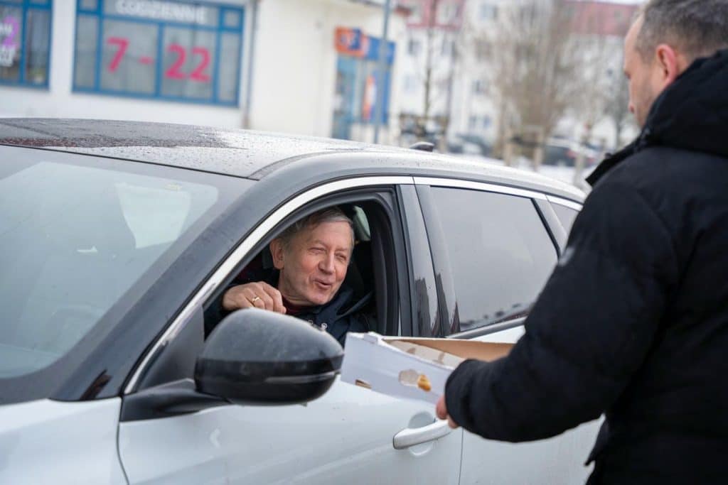 Prezydent Szewczyk rozdaje pączki mieszkańcom na ulicy w centrum Olsztyna.