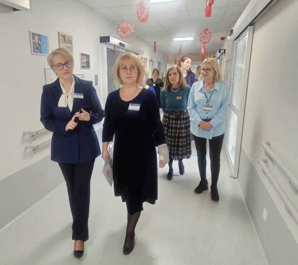 Grupa os&oacute;b spaceruje po nowoczesnym korytarzu szpitala dziecięcego w Olsztynie.