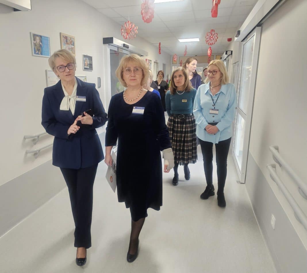 Grupa os&oacute;b spaceruje po nowoczesnym korytarzu szpitala dziecięcego w Olsztynie.