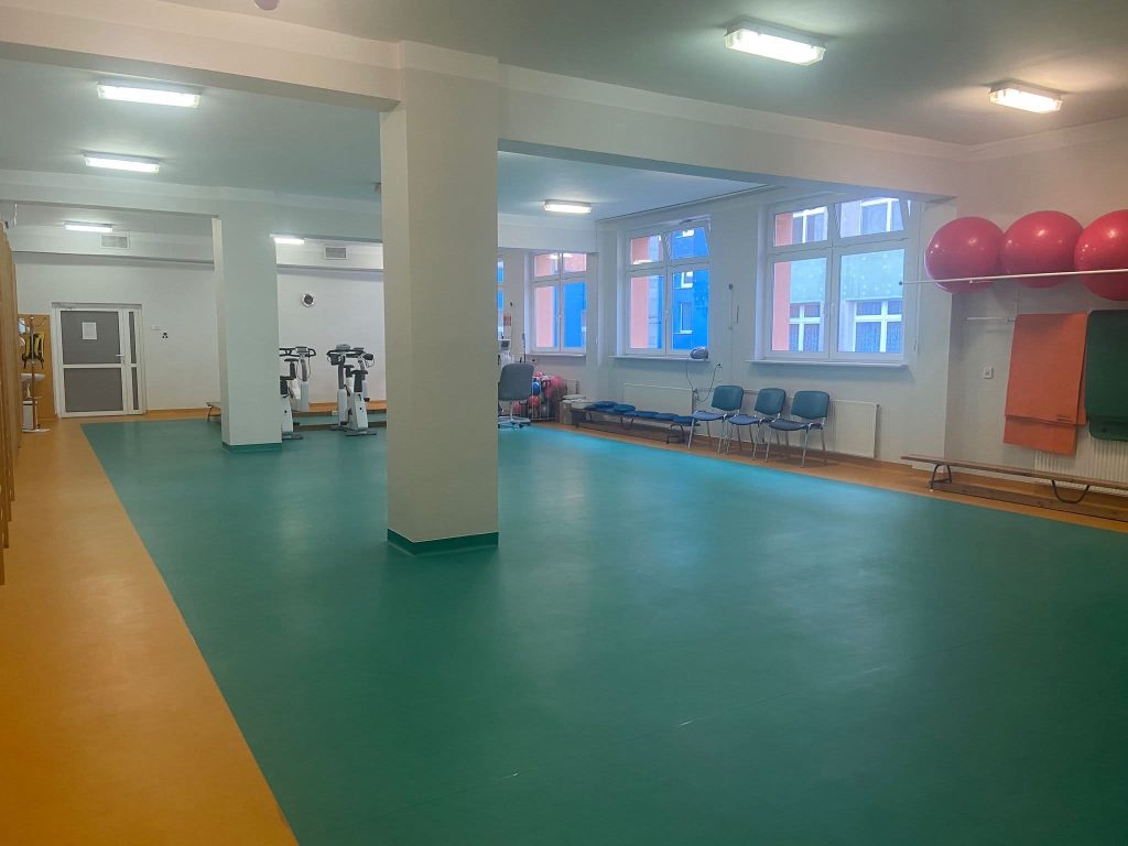 Przestrzeń w szpitalu z dużymi oknami, pływającymi piłkami i miejscami do siedzenia.