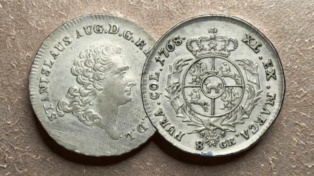 Dwie stare monety, jedna z portretem kobiety, druga z herbem, na brązowej powierzchni.