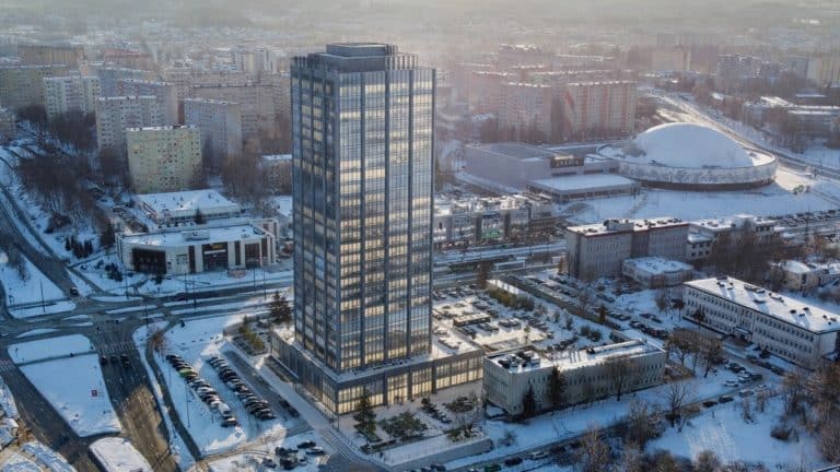 Wysoki wieżowiec w Olsztynie na tle miejskiej zabudowy zimą, z planami rozbudowy na 30 pięter.