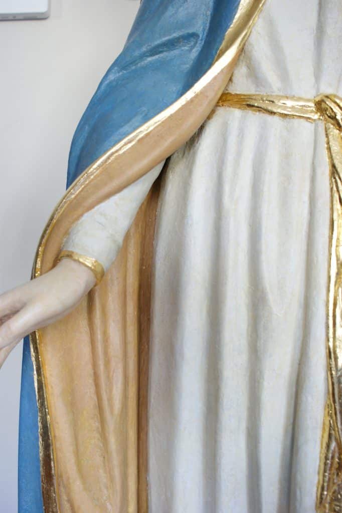 Zbliżenie na fragment figury Matki Bożej w Gietrzwałdzie, ukazujące szczeg&oacute;ły stroju i złote wykończenia.