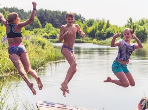 dzieci skaczące do wody w czasie pobytu na koloniach letnich na mazurach