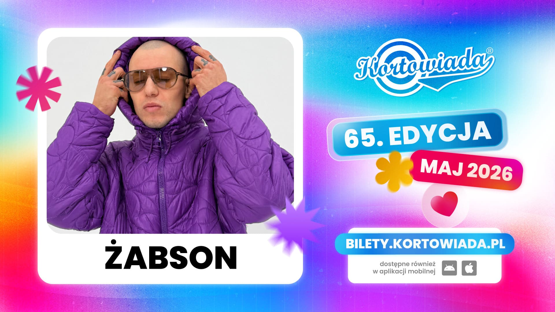 Zdjęcie rapera w fioletowej kurtce i okularach, trzymającego kaptur na głowie, na tle kolorowego plakatu.