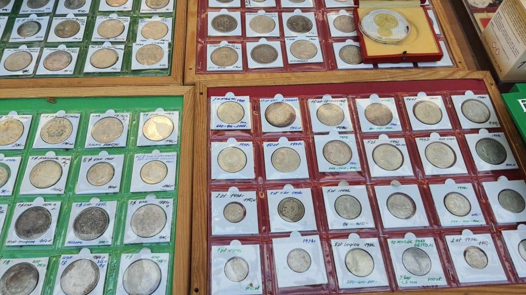 Stare monety i banknoty w drewnianych gablotach na giełdzie kolekcjonerskiej.