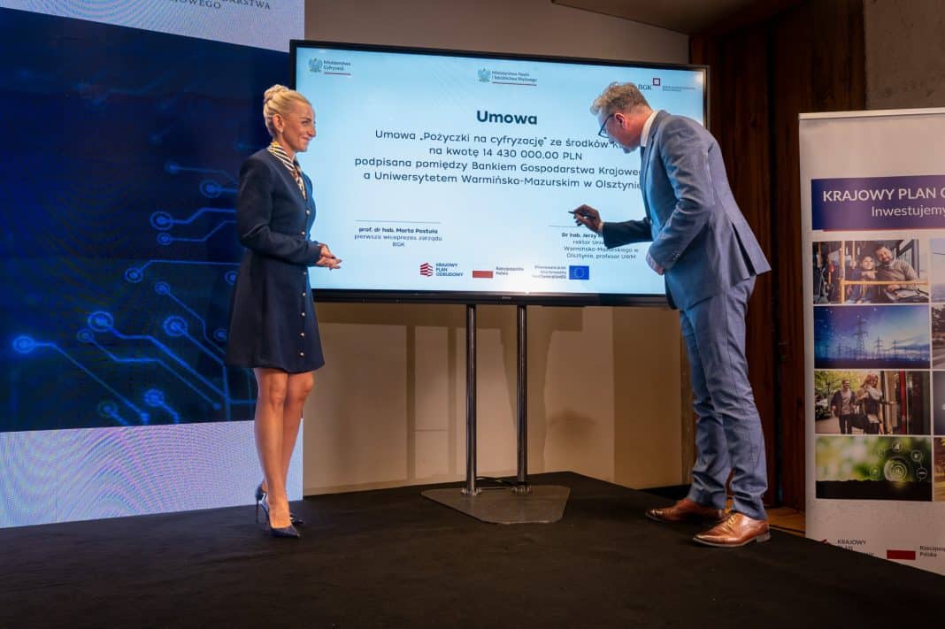 Uczestnicy podpisują umowę na dofinansowanie uczelni podczas konferencji, na ekranie widnieje treść umowy.