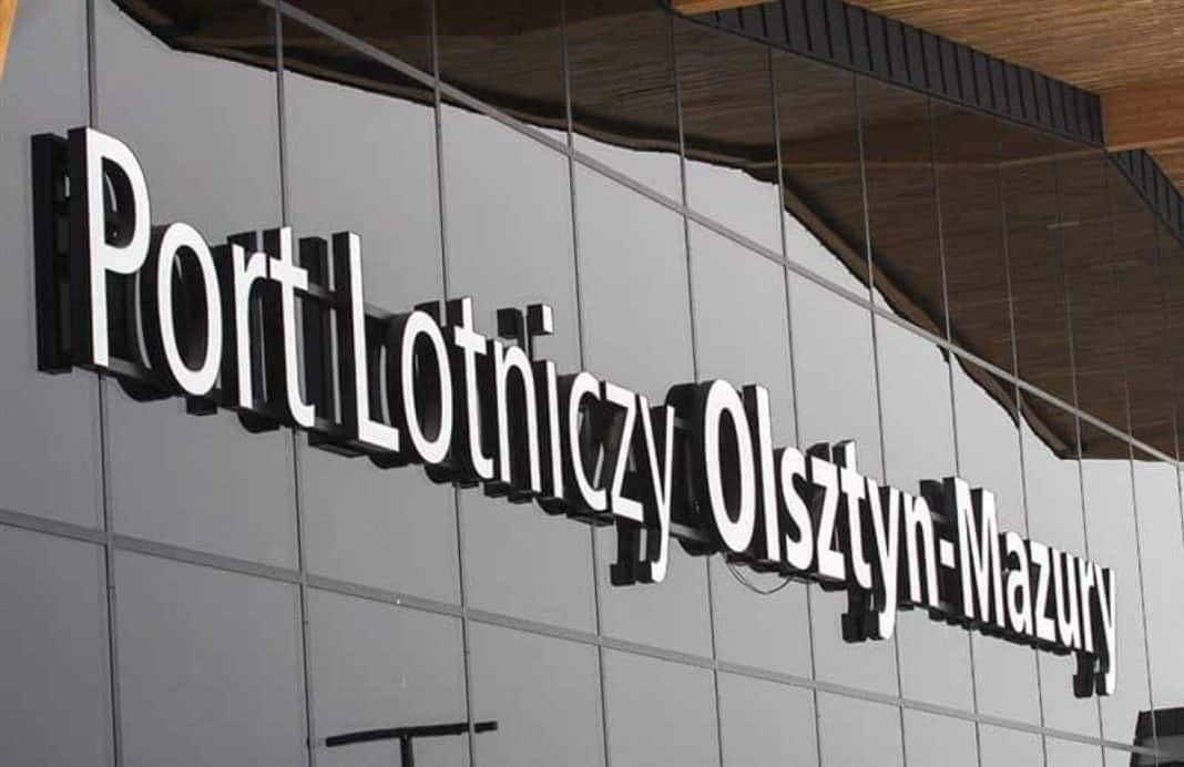 Widok na znak portu lotniczego Olsztyn-Mazury na zewnątrz budynku.
