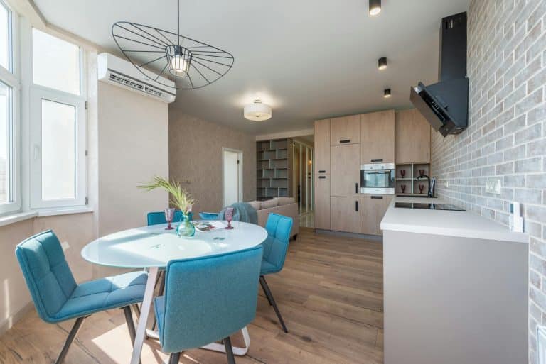 Przytulne wnętrze z jadalnią, kuchnią i nowoczesnym oświetleniem, w jasnych kolorach i naturalnych materiałach.