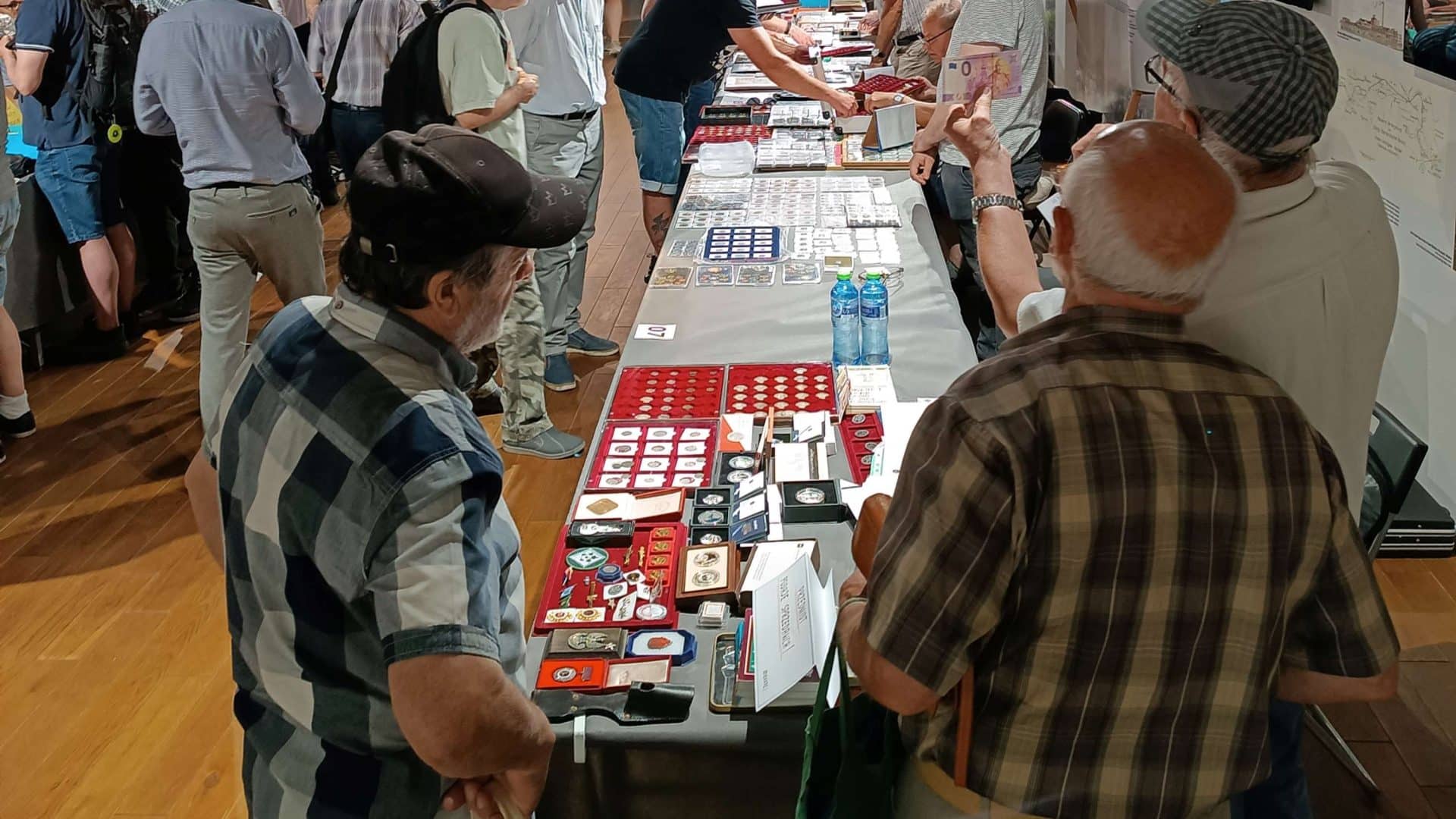 Stolik z kolekcjonerskimi monetami i medalami podczas giełdy w Olsztynie.