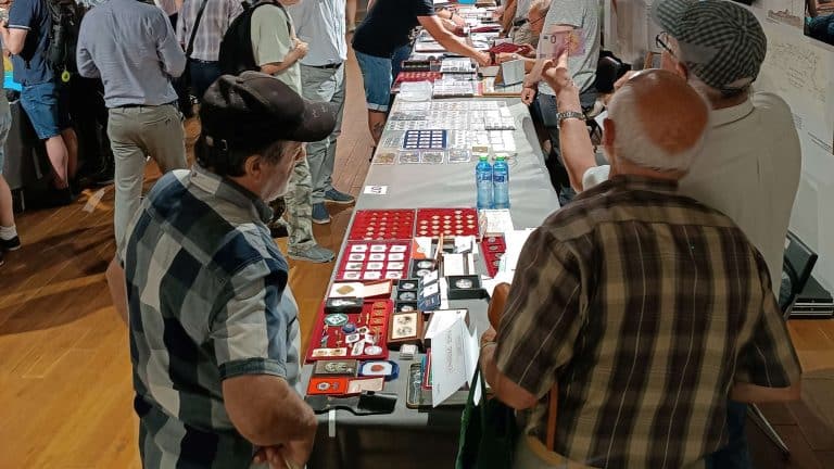 Stolik z kolekcjonerskimi monetami i medalami podczas giełdy w Olsztynie.