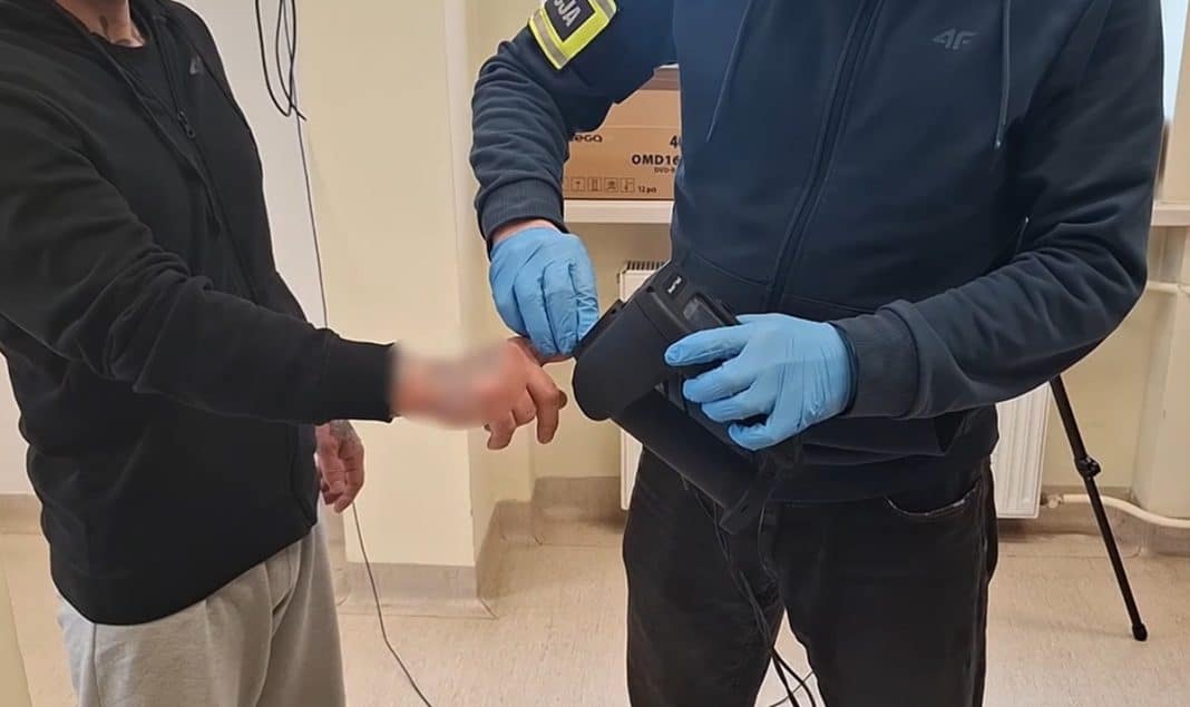 Policjant sprawdza dokumenty osoby w sklepie, trzymając urządzenie do pomiaru.