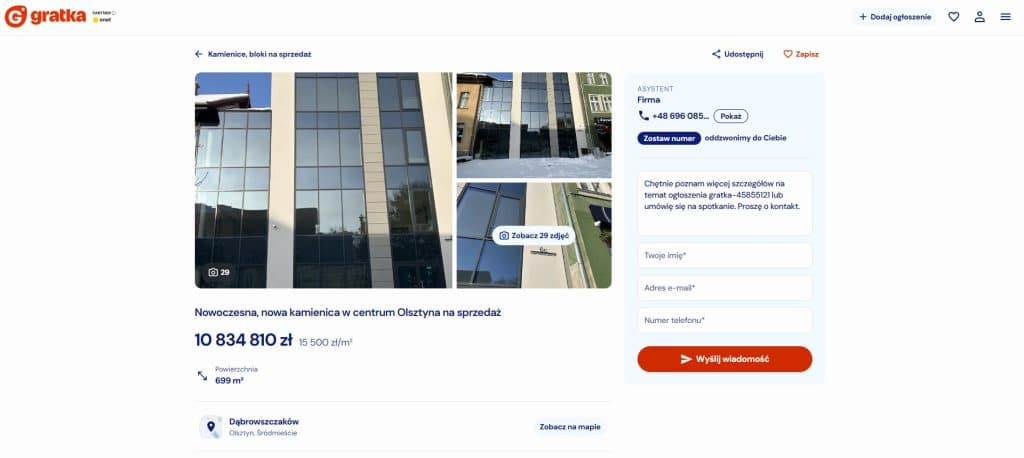 Nowoczesny, szklany budynek w centrum Olsztyna, wystawiony na sprzedaż, z widokiem na ulicę i sąsiednie budynki.
