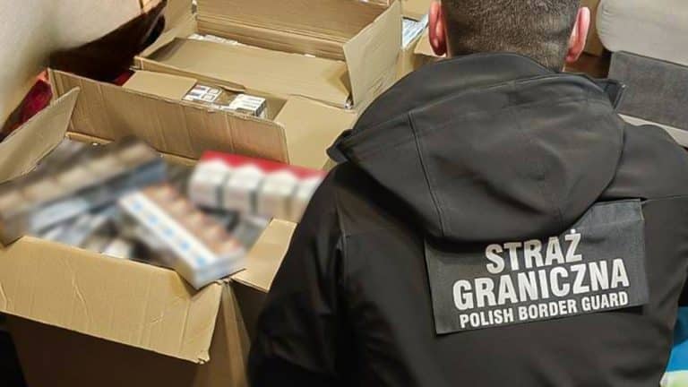 Funkcjonariusz Straży Granicznej przy kartonach z ukrytymi przedmiotami w garażu.