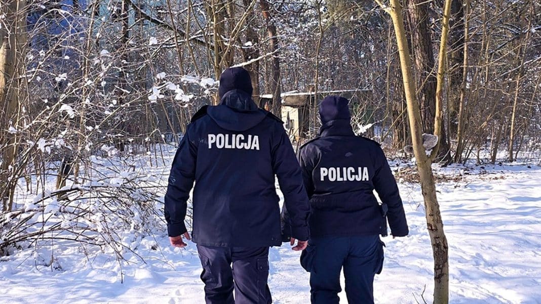 Dwoje policjant&oacute;w w zimowym lesie na Mazurach, prowadzący dochodzenie po śladach przestępstwa.