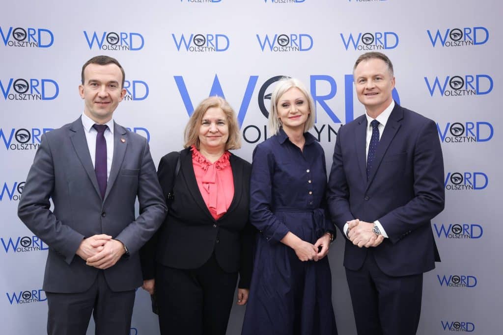 Grupa czterech os&oacute;b na tle logo WORD Olsztyn, podczas oficjalnego otwarcia filii w Ełku.
