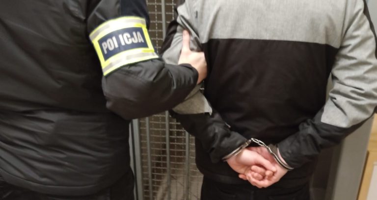 Policjant trzyma mężczyznę w rękach podczas interwencji w mieszkaniu.