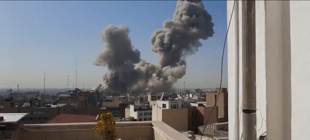 Widok na dym unoszący się nad miastem po ataku lotniczym, w tle niebo bez chmur.