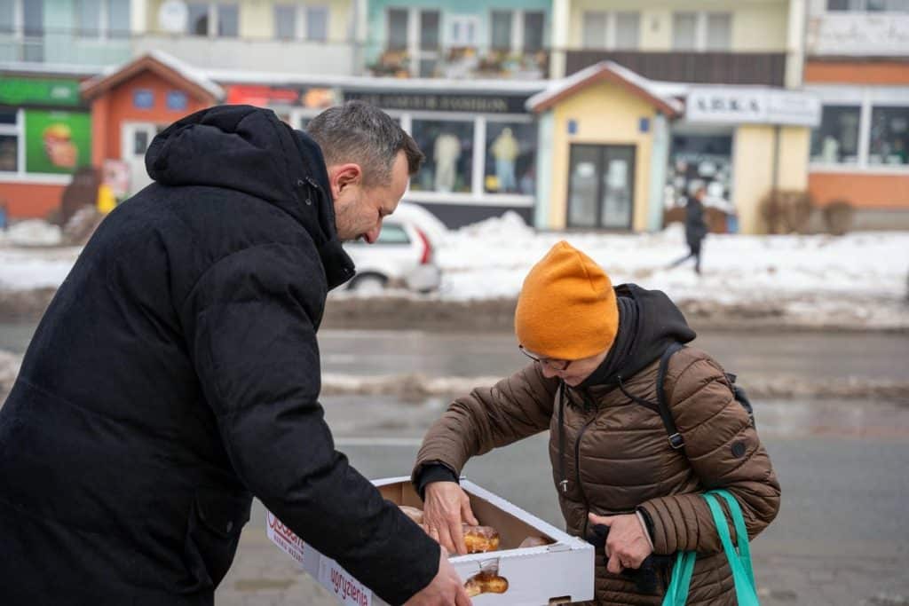 Prezydent Olsztyna rozdaje pączki mieszkańcom na ulicy w centrum miasta.
