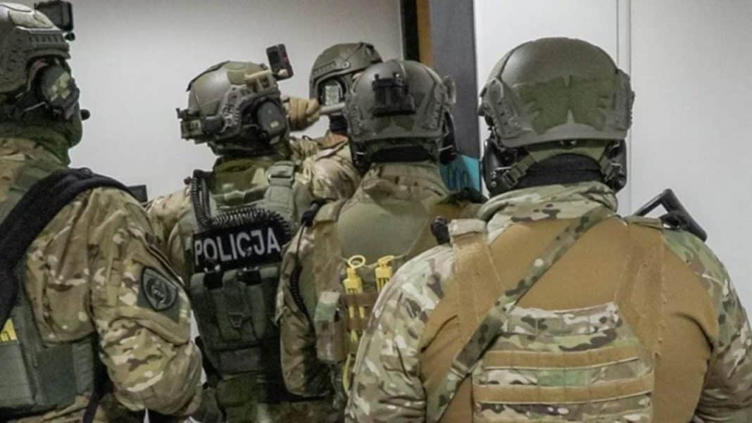 Grupa policjant&oacute;w w kamuflażu podczas akcji zatrzymania w budynku.