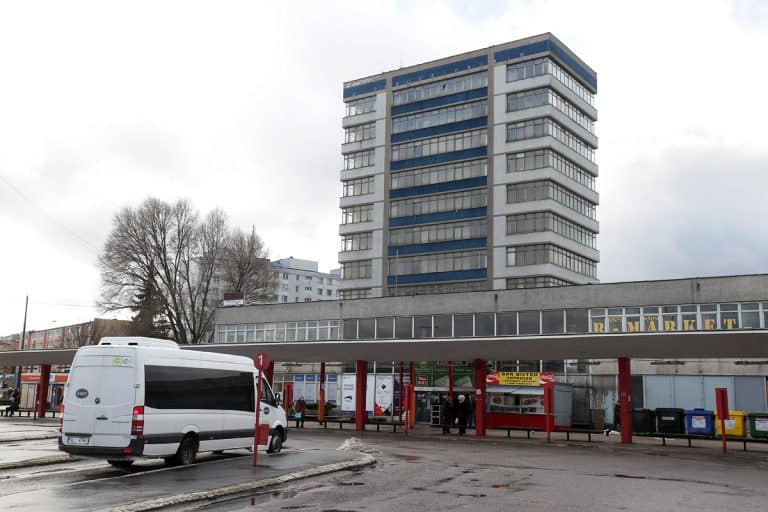 Widok dawnego dworca autobusowego w centrum Olsztyna z autobusem i budynkiem w tle.