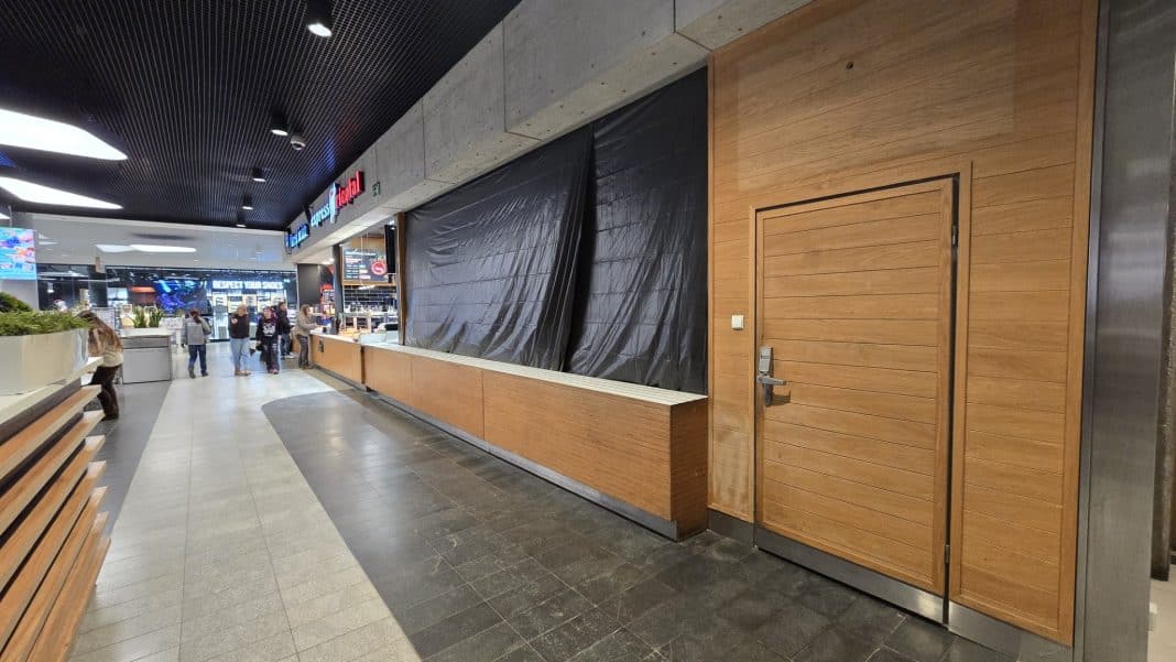 Zamknięte stanowisko gastronomiczne w centrum handlowym, z zasłoniętymi oknami i pustą przestrzenią.