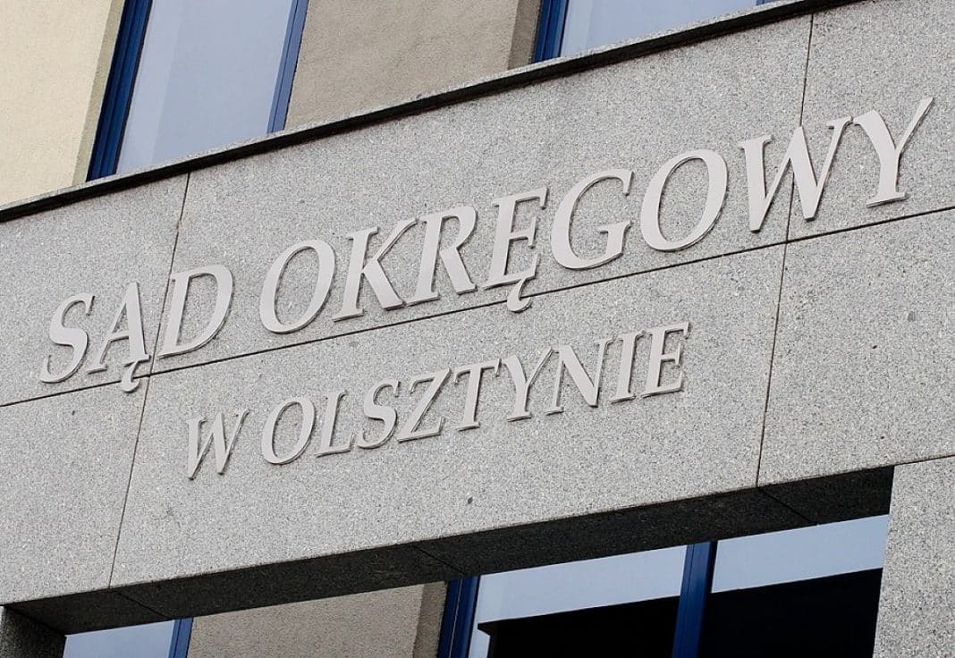 Widok na budynek Sądu Okręgowego w Olsztynie z widocznym napisem na ścianie.