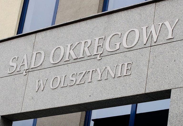 Widok na budynek Sądu Okręgowego w Olsztynie z widocznym napisem na ścianie.