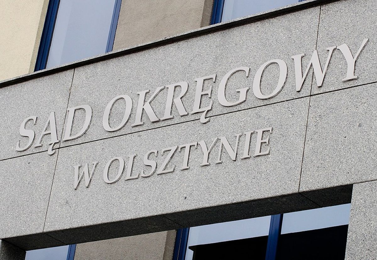 Widok na budynek Sądu Okręgowego w Olsztynie z widocznym napisem na ścianie.