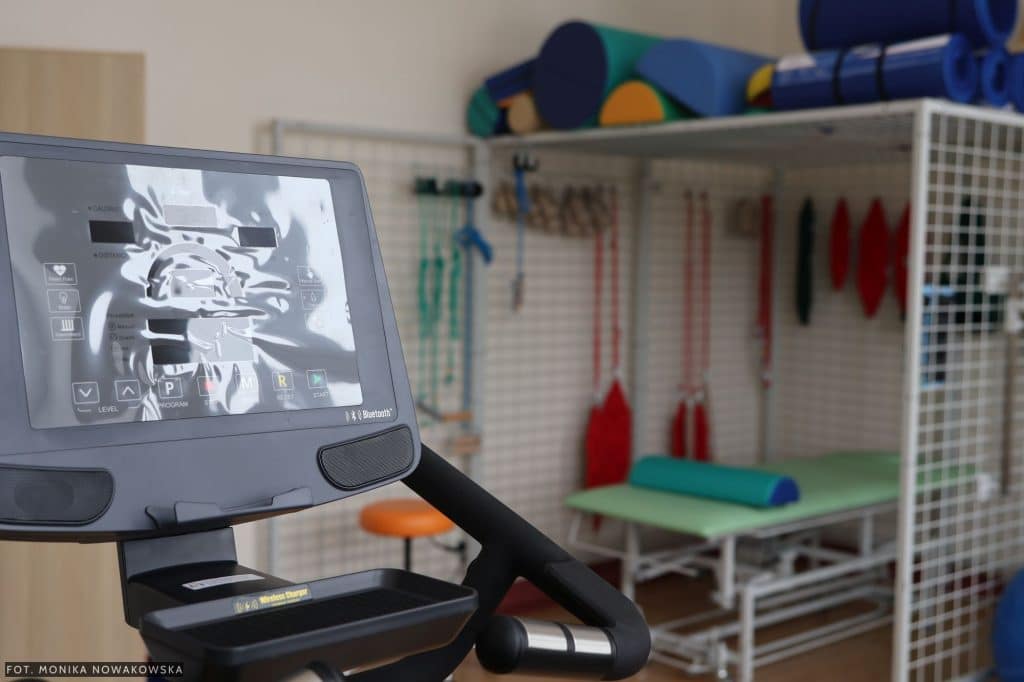 Nowoczesny sprzęt rehabilitacyjny w ośrodku w Barczewie, w tle sala z urządzeniami i wyposażeniem.