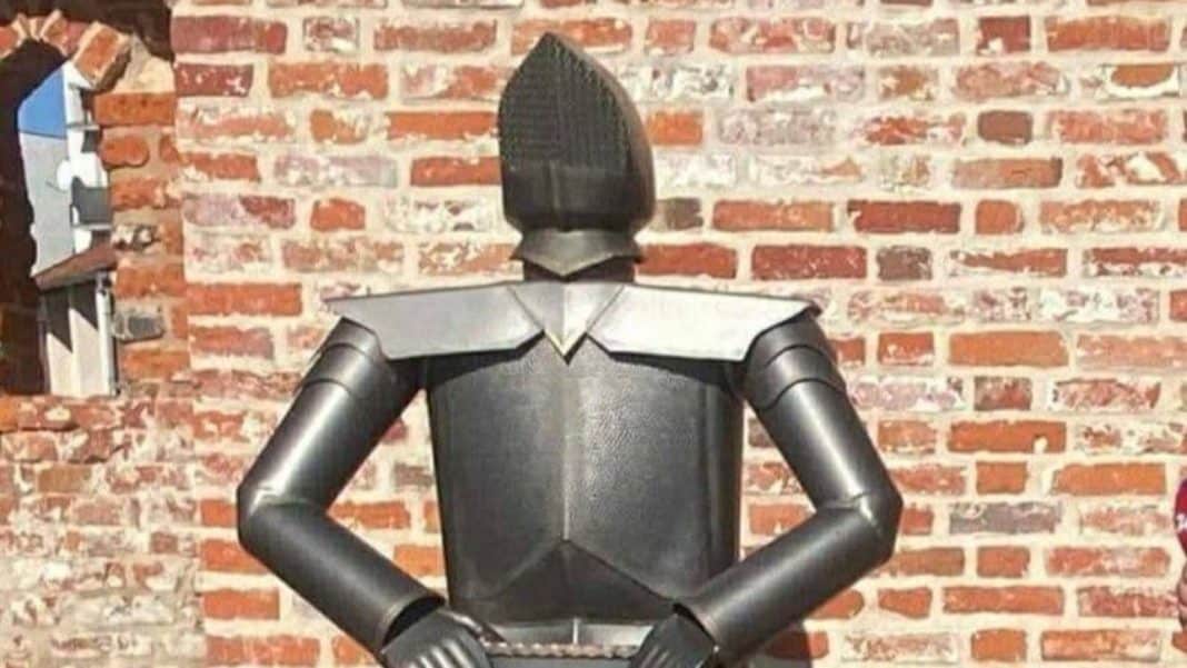 Zabytkowa figura rycerza z uszkodzoną głową, ustawiona przy murze w Pasłęku.