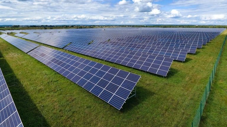 Widok na rozległą farmę fotowoltaiczną na zielonym terenie pod Olsztynem.
