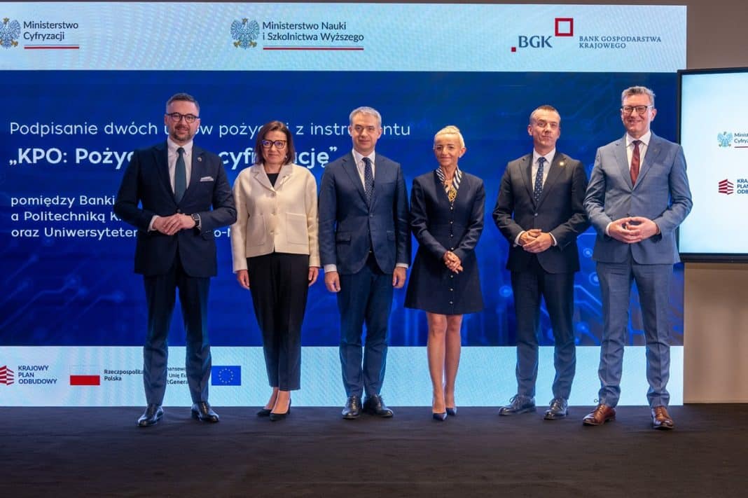 Grupa siedmiu os&oacute;b na tle ekranu podczas podpisania umowy, oficjalne wydarzenie.