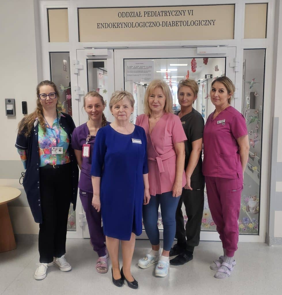 Grupa pracownik&oacute;w szpitala przed wejściem do oddziału pediatrycznego w Olsztynie.