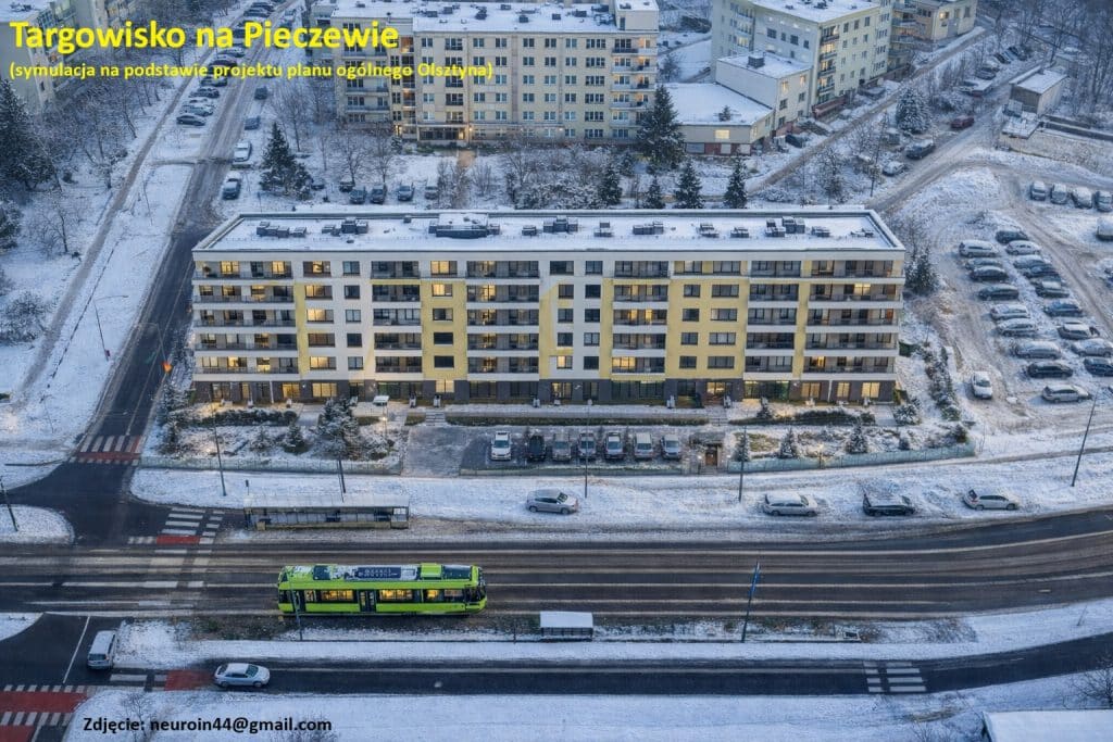 Widok na nowoczesny wieżowiec i otaczający go las w zimowej scenerii, z oświetlonymi oknami i zaparkowanymi samochodami.