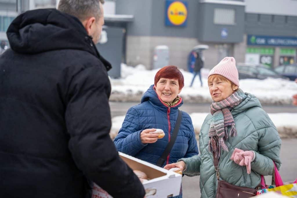 Prezydent Olsztyna rozdaje pączki mieszkańcom na ulicy w centrum miasta.