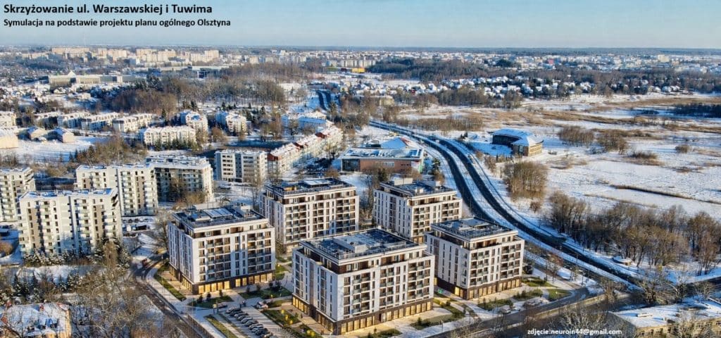 Widok na nowoczesne budynki mieszkalne w zimowej scenerii, z lasami i wieżowcami w tle.