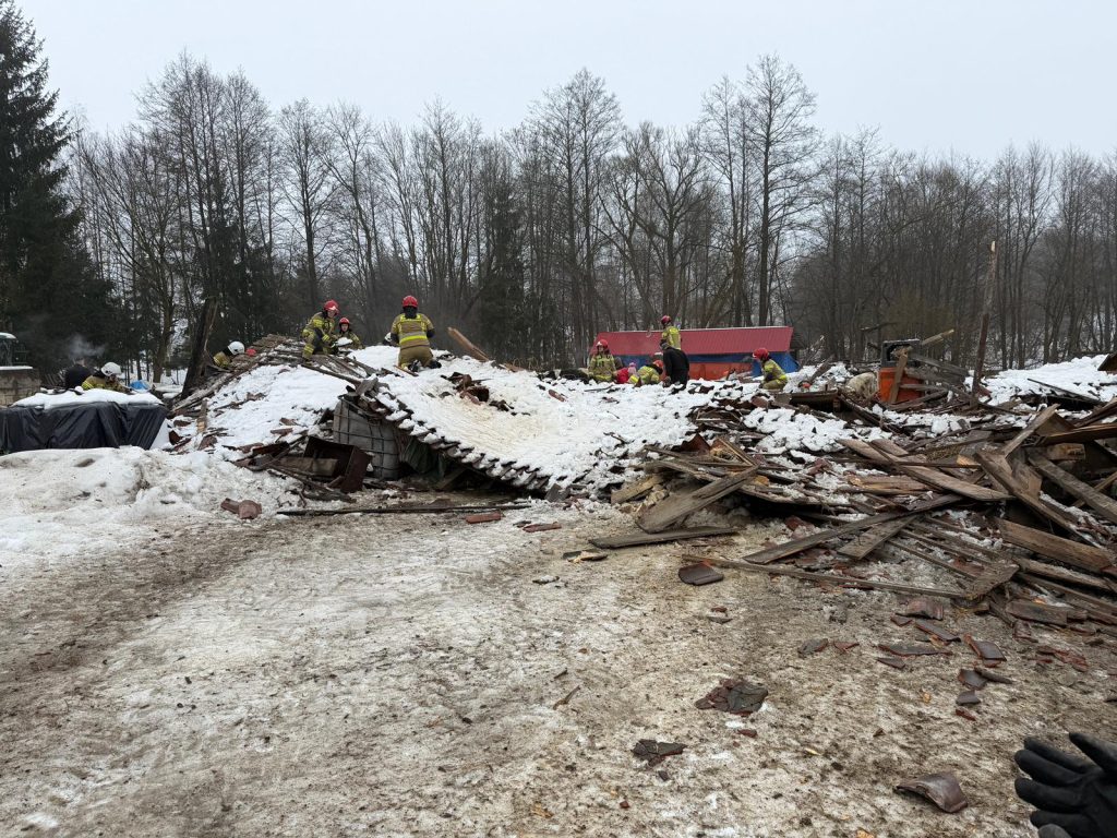 Strażacy ratunkowi pracują przy zawalonym dachu stodoły, pod kt&oacute;rym są zwierzęta, w zimowej scenerii.