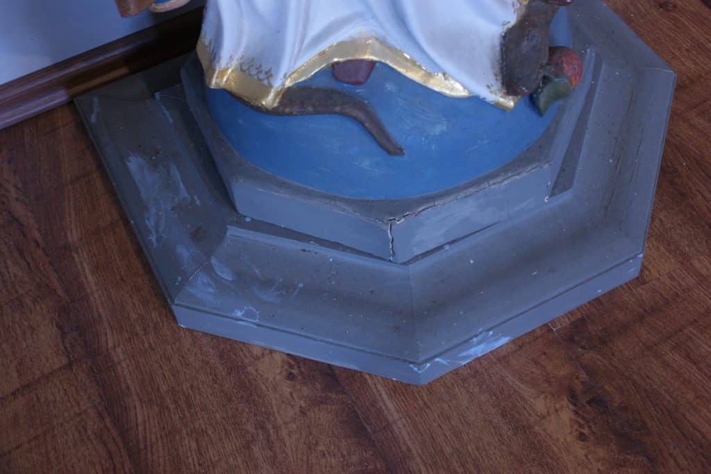 Zdjęcie podstawy figury Matki Bożej w Gietrzwałdzie, z widocznymi uszkodzeniami i zabrudzeniami.