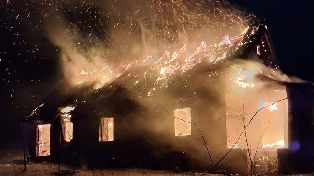 Pożar domu na Mazurach, ogień i dym widoczne w nocy, strażacy walczą z ogniem.