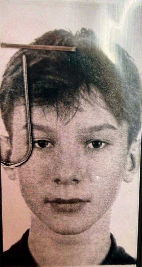 Portret chłopca z kr&oacute;tkimi włosami i poważnym wyrazem twarzy, na czarno-białym zdjęciu.