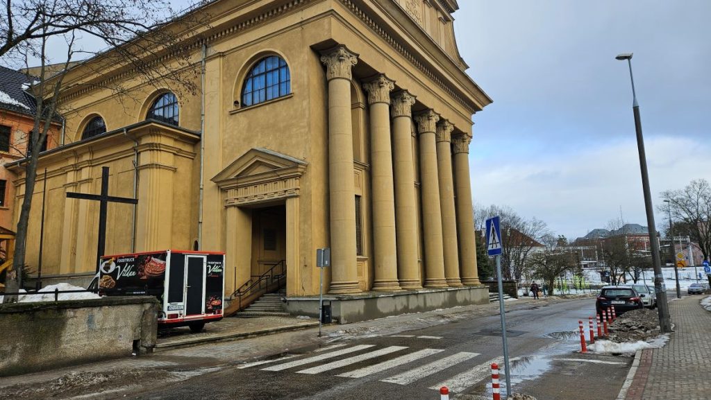 Food truck z kawą i jedzeniem ustawiony przed kościołem na Zatorzu, zimowa pogoda, śnieg i mokra ulica.