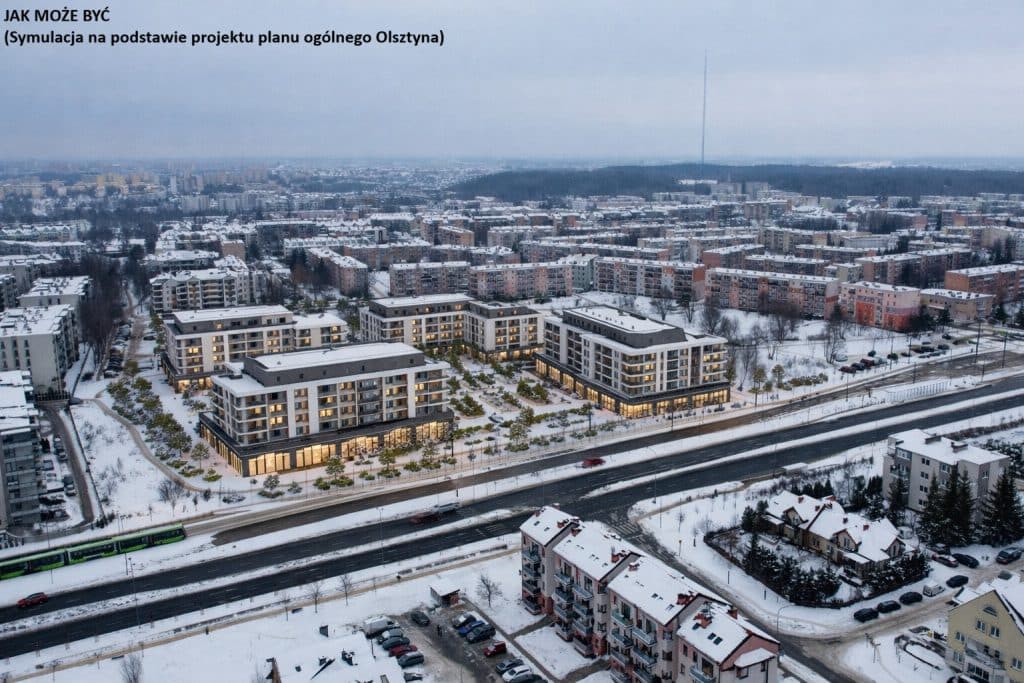 Widok na nowoczesne osiedle mieszkaniowe w zimowej scenerii, z wieżowcami i lasami w tle.