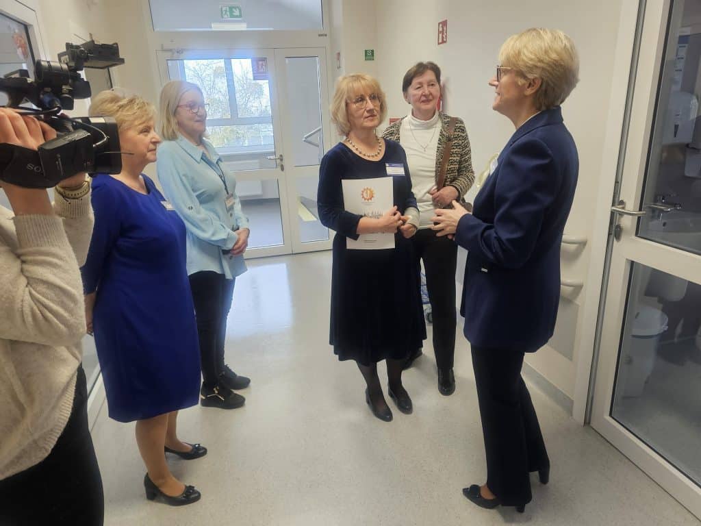 Grupa kobiet rozmawia w nowoczesnym oddziale szpitala dziecięcego, widoczne nowe sale i monitoring.