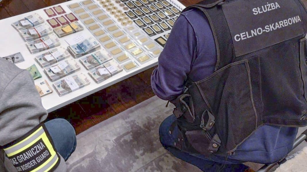 Na zdjęciu widoczny jest funkcjonariusz służb celno-skarbowych przy stole z pieniędzmi i innymi przedmiotami.